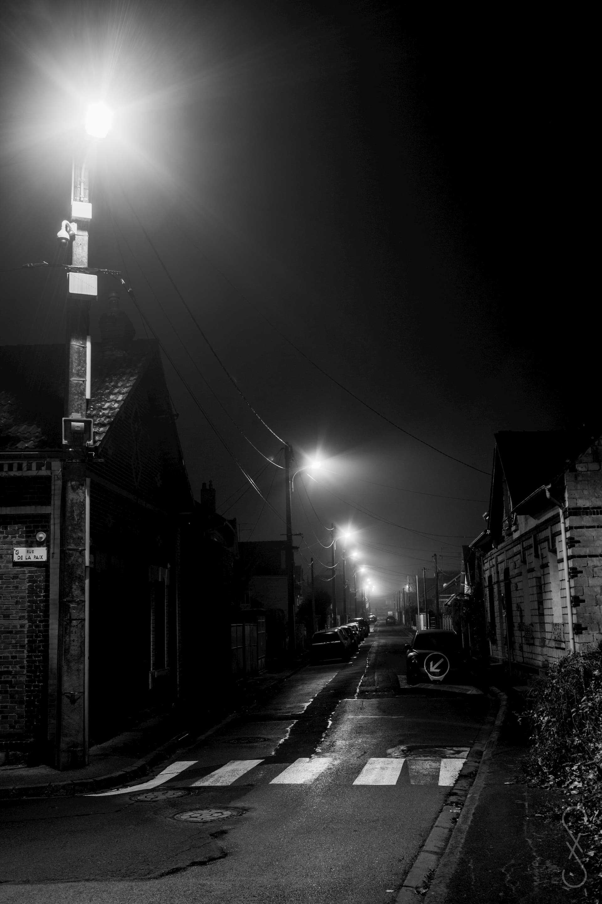 Une rue déserte de nuit, des lampadaires allumés, s'enfuit dans l'horizon.